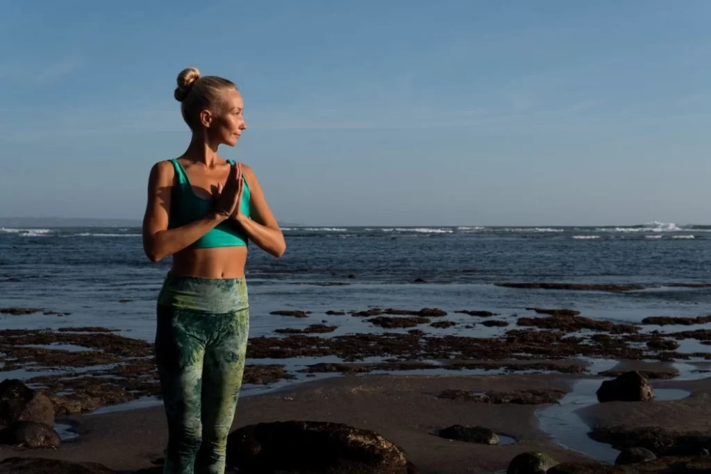 Woman meditating peacefully on a beach during sunset