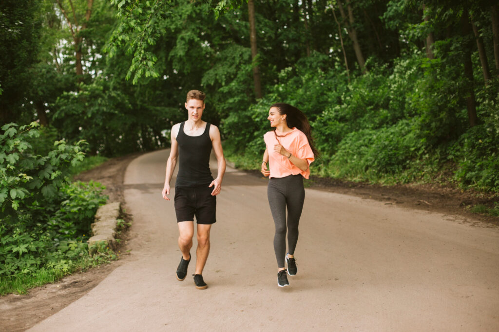 Two people alternating between walking and running in a park, practicing the walk/run technique.