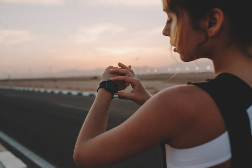 Female runner checking her watch to monitor running pace.